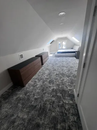 Renovated upstairs room with carpet flooring and rebuilt wall layout